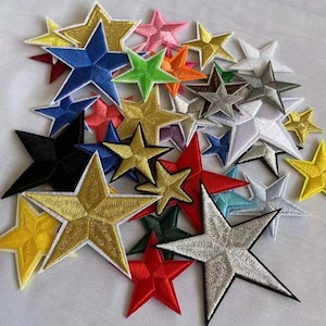 May include: A collection of embroidered star patches in various colors, including gold, silver, red, blue, and green. Each star has a white border. These patches are suitable for decorating clothing or accessories.