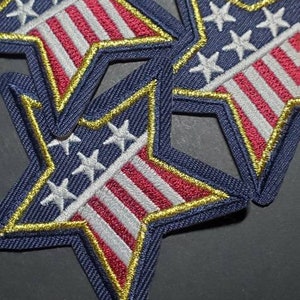 May include: Three blue star-shaped patches with a red, white, and blue American flag design. The stars are white and the flag is embroidered with gold thread.