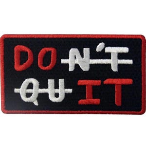 May include: Black rectangular patch with a red border. The patch features the words "DON'T QUIT" in red and white, with the word "QUIT" crossed out. The patch is designed to be sewn or ironed onto fabric.