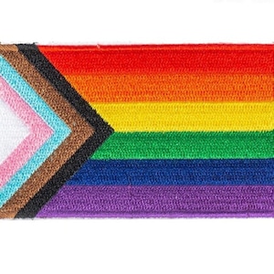 May include: A rainbow pride flag patch with a brown, black, light blue, pink, white, yellow, green, blue, and purple stripes. The patch has a chevron design on the left side.