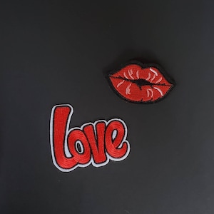 May include: Red felt patches with the word "love" and a red felt patch of a pair of lips.