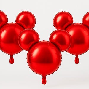 Puede incluir: Globos rojos de aluminio con forma de cabeza de Mickey Mouse. Los globos tienen un acabado brillante y met&aacute;lico y est&aacute;n dispuestos en grupo. Cada globo tiene una peque&ntilde;a cola colgante.