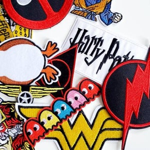 Puede incluir: Un conjunto de parches bordados coloridos con personajes y logotipos de la cultura pop. Incluye un parche de Deadpool, un parche de Goku, un logotipo de Wonder Woman y un parche de Harry Potter. Los parches son de varias formas y tama&ntilde;os.