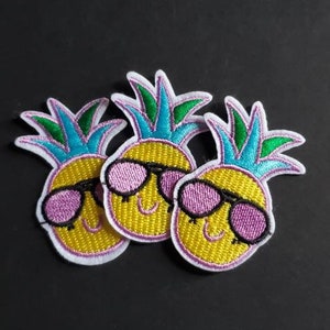 May include: Three yellow pineapple-shaped embroidered patches with pink sunglasses and green and blue leaves.