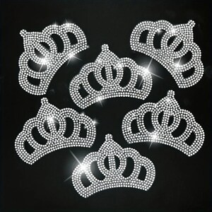 May include: Six silver rhinestone crown iron-on patches. The crowns are all the same design, with a pointed top and five points. The rhinestones are small and closely spaced, creating a sparkling effect.