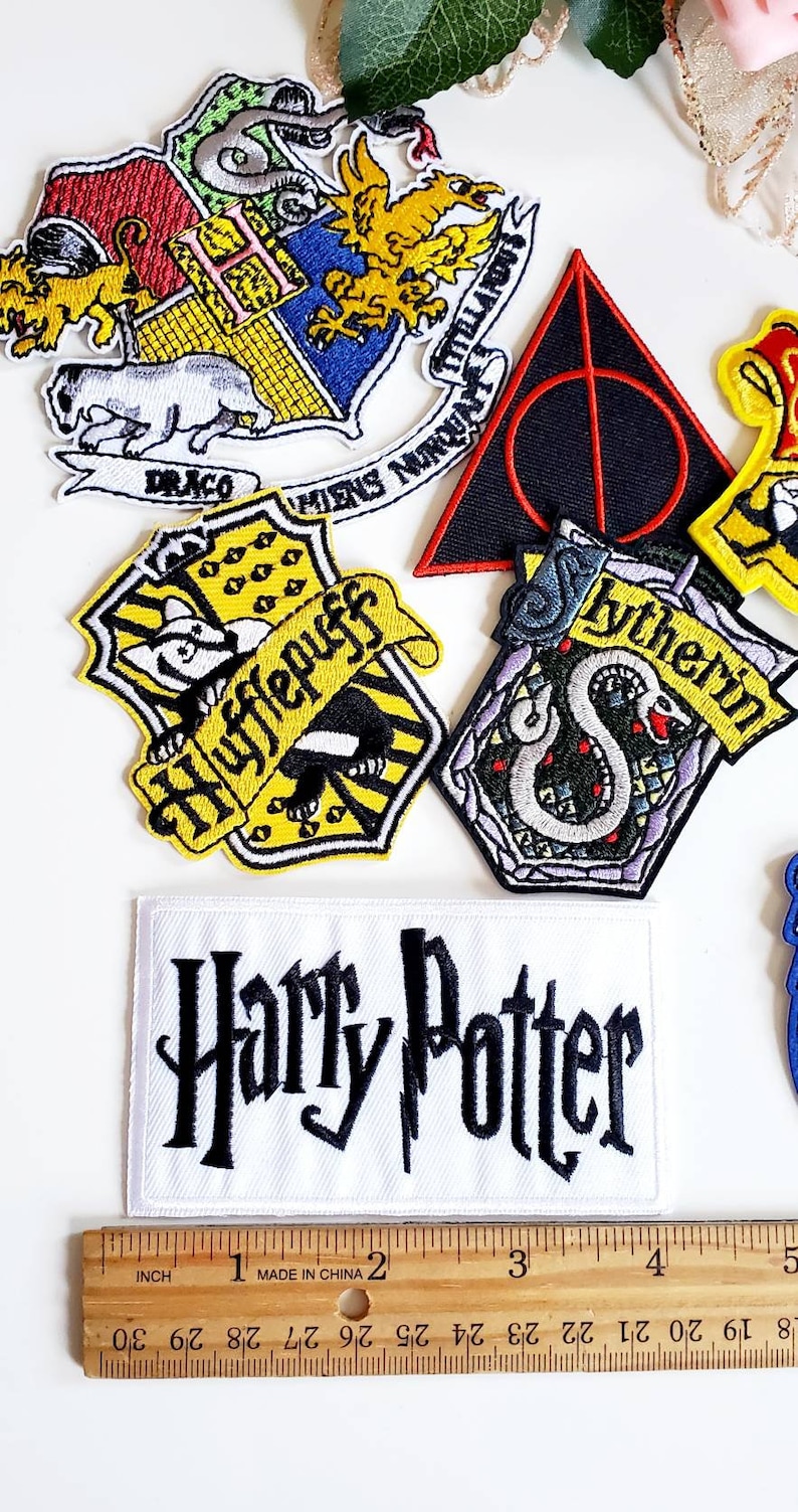 Puede incluir: Un conjunto de parches bordados con dise&ntilde;os de la serie Harry Potter. Incluye parches con los escudos de las casas de Hogwarts, el s&iacute;mbolo de las Reliquias de la Muerte y el logotipo de Harry Potter. Una regla muestra pulgadas, con medidas en cent&iacute;metros.