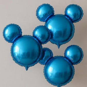 Puede incluir: Tres globos azules de papel de aluminio con forma de cabeza de rat&oacute;n y dos orejas redondas. Los globos brillantes son de un azul vivo y est&aacute;n colocados sobre un fondo blanco liso. Adecuados para una fiesta de cumplea&ntilde;os u otra celebraci&oacute;n.