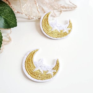 May include: Two white felt patches with gold embroidered crescent moons and white stars.