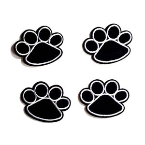 May include: Four black paw print iron-on patches with white stitching. The paw prints are approximately 1 inch in diameter.