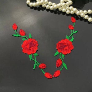 May include: Two red embroidered rose patches with green stems and leaves. The roses have a detailed design with multiple layers of petals.