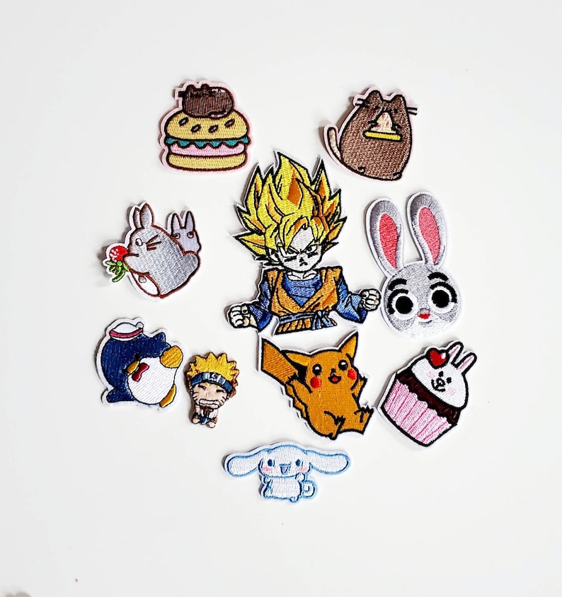 Puede incluir: Una colecci&oacute;n de parches bordados con varios personajes de dibujos animados y alimentos. Incluye un personaje de anime de pelo amarillo, un conejo gris con orejas rosas, un ping&uuml;ino, una magdalena y una hamburguesa.