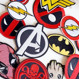 Puede incluir: Colecci&oacute;n de parches bordados con personajes de c&oacute;mics y superh&eacute;roes. Los dise&ntilde;os incluyen el logotipo de los Vengadores, el escudo del Capit&aacute;n Am&eacute;rica, el s&iacute;mbolo de Batman y el rayo de Flash. Otros parches presentan a Deadpool, Groot y el emblema de Wonder Woman.