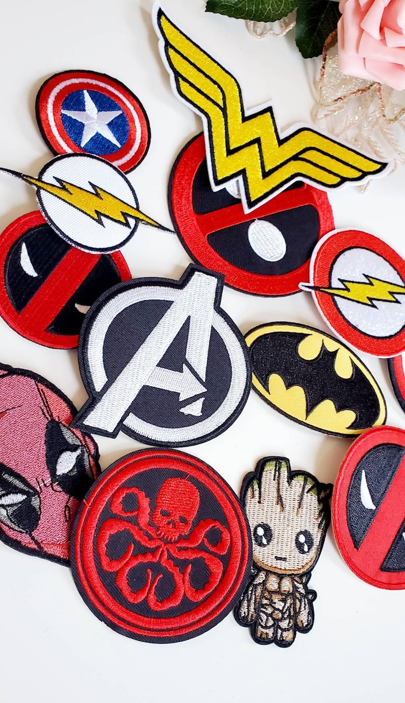 Puede incluir: Colecci&oacute;n de parches bordados con personajes de c&oacute;mics y superh&eacute;roes. Los dise&ntilde;os incluyen el logotipo de los Vengadores, el escudo del Capit&aacute;n Am&eacute;rica, el s&iacute;mbolo de Batman y el rayo de Flash. Otros parches presentan a Deadpool, Groot y el emblema de Wonder Woman.