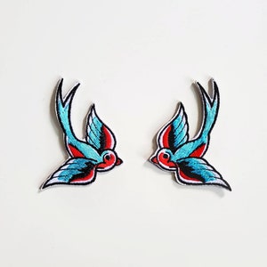 Peut inclure: Deux patchs brodés d'hirondelles bleues et rouges. Les oiseaux sont tournés dans des directions opposées.