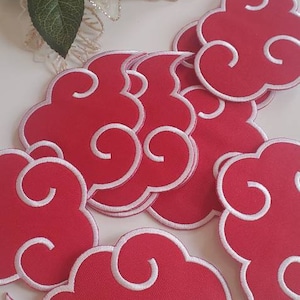 May include: A set of red and white embroidered iron-on patches shaped like clouds. The clouds have a white outline and a swirling design.