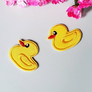 May include: Two yellow felt iron-on patches shaped like rubber duckies. The duckies have black eyes and red beaks.