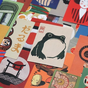 Puede incluir: Una colección de coloridas tarjetas de temática japonesa con ilustraciones de geishas, muñecas daruma, una rana e imágenes tradicionales japonesas. Las tarjetas tienen varias formas y tamaños, con una mezcla de tonos rojos, naranjas y amarillos.