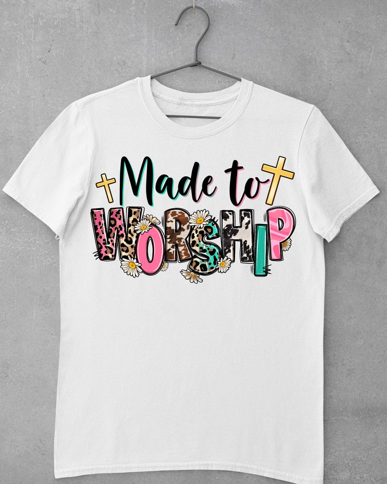 May include: White t-shirt with the text "Made to Worship" in colorful letters with animal print and floral accents.