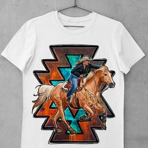 May include: White t-shirt featuring a graphic of a woman riding a horse. The horse is a light brown color, and the rider is wearing a cowboy hat and blue jeans. The graphic is set against a geometric design with orange, teal, and black accents.