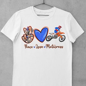 May include: White t-shirt with a peace sign, heart, and a motocross rider. The peace sign is made up of smaller motocross riders. The text "Peace Love Motocross" is below the design.