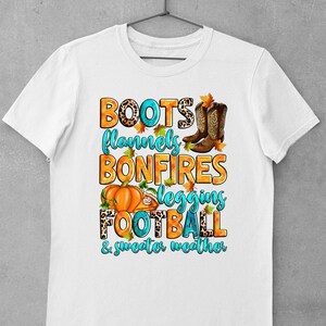 May include: White t-shirt with a graphic design featuring the text "Boots, flannels, bonfires, leggings, football, & sweater weather" with images of boots, a pumpkin, a football, and autumn leaves.