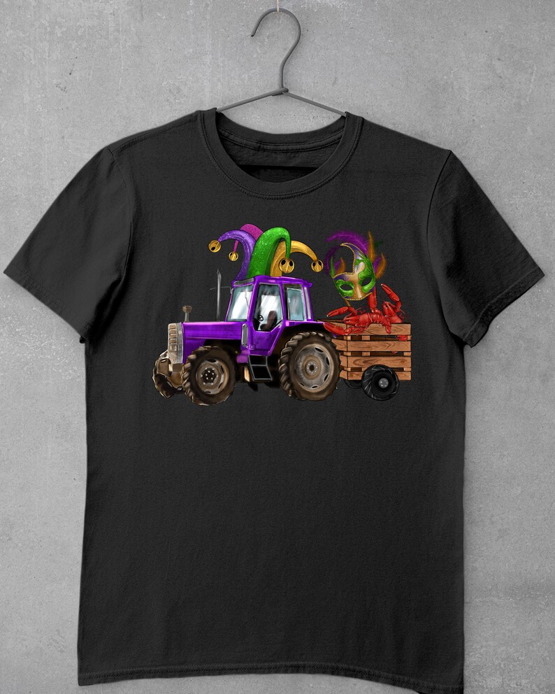 Pu&ograve; includere: Una maglietta nera con un trattore viola che tira un carro con un gambero rosso che indossa un cappello da giullare viola, verde e oro.