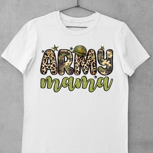 May include: White t-shirt with the text "ARMY mama" in a camouflage and leopard print design. The word "ARMY" features a military helmet graphic. The shirt is hanging on a hanger against a gray background.