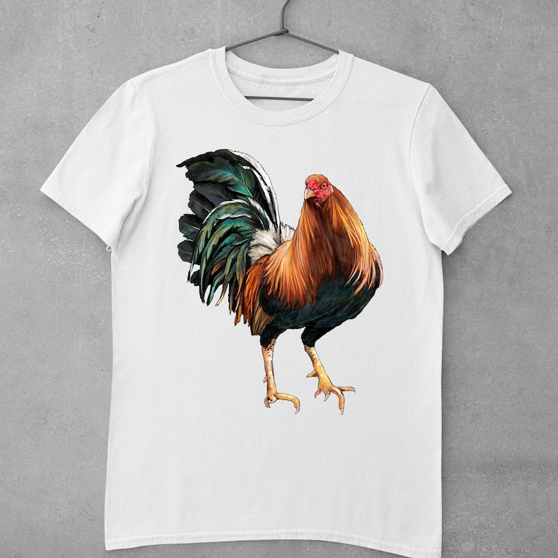 May include: A white t-shirt with a colorful illustration of a rooster. The rooster has a red comb, a green and blue tail, and brown and black feathers.