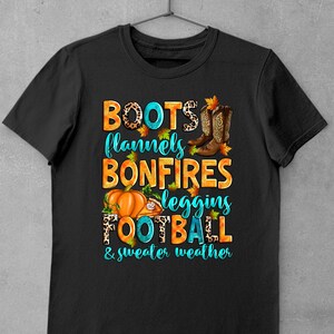 May include: Black t-shirt with a graphic design featuring the text "BOOTS, flannels, BONFIRES, leggings, FOOTBALL & sweater weather" in turquoise and orange with autumn-themed imagery.