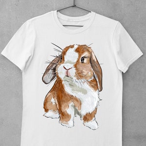May include: A white t-shirt with a brown and white rabbit illustration. The rabbit has long ears and is looking at the viewer.