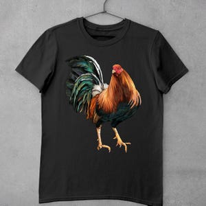 May include: Black t-shirt with a colorful rooster illustration. The rooster has a red comb and wattle, a green and blue tail, and a brown and black body.