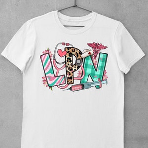 May include: White t-shirt with a graphic design of the letters LPN in colorful patterns, surrounded by medical symbols like a stethoscope, a syringe, and a caduceus.
