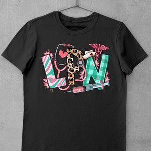 May include: Black t-shirt with a graphic of the letters LPN in different colors and patterns. The letters are decorated with medical symbols, including a stethoscope, a syringe, and a caduceus.