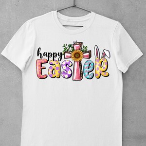 May include: White t-shirt with a colorful "Happy Easter" graphic. The graphic features a pink cross with a sunflower, bunny ears, and Easter eggs.