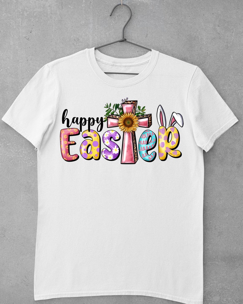 May include: White t-shirt with a colorful "Happy Easter" graphic. The graphic features a pink cross with a sunflower, bunny ears, and Easter eggs.