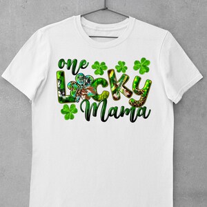 May include: White t-shirt with a green, black, and brown graphic that says "one lucky mama" with four green shamrocks.