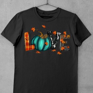 May include: Black t-shirt with a graphic of the word "LOVE" made of different patterned fabrics. The "O" is a teal pumpkin with a stem and a brown pinecone.