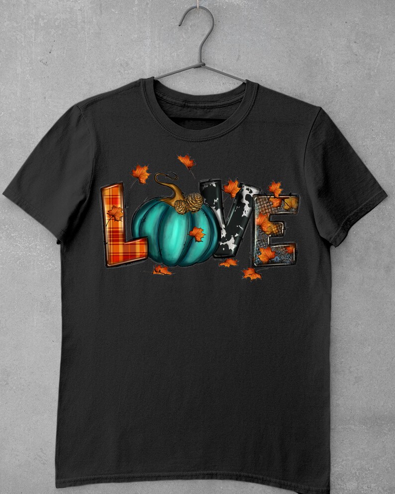 May include: Black t-shirt with a graphic of the word "LOVE" made of different patterned fabrics. The "O" is a teal pumpkin with a stem and a brown pinecone.
