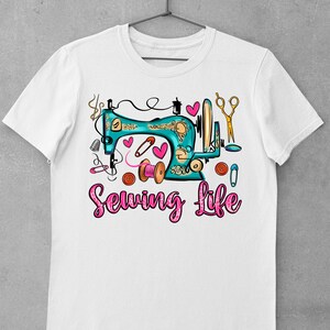 Op de afbeelding: Wit T-shirt met een turquoise naaimachine-afbeelding en de tekst "Sewing Life" in roze glitterletters. De afbeelding bevat roze harten, een schaar, knopen en een spoel met garen.