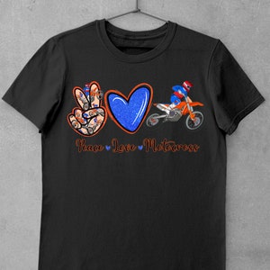 May include: Black t-shirt with a peace sign, heart, and motocross rider graphic. The peace sign is made up of smaller motocross riders. The text "Peace Love Motocross" is below the graphic.