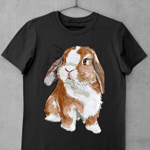 May include: A black t-shirt with a cartoon illustration of a brown and white lop-eared rabbit. The rabbit is looking directly at the viewer with a curious expression.