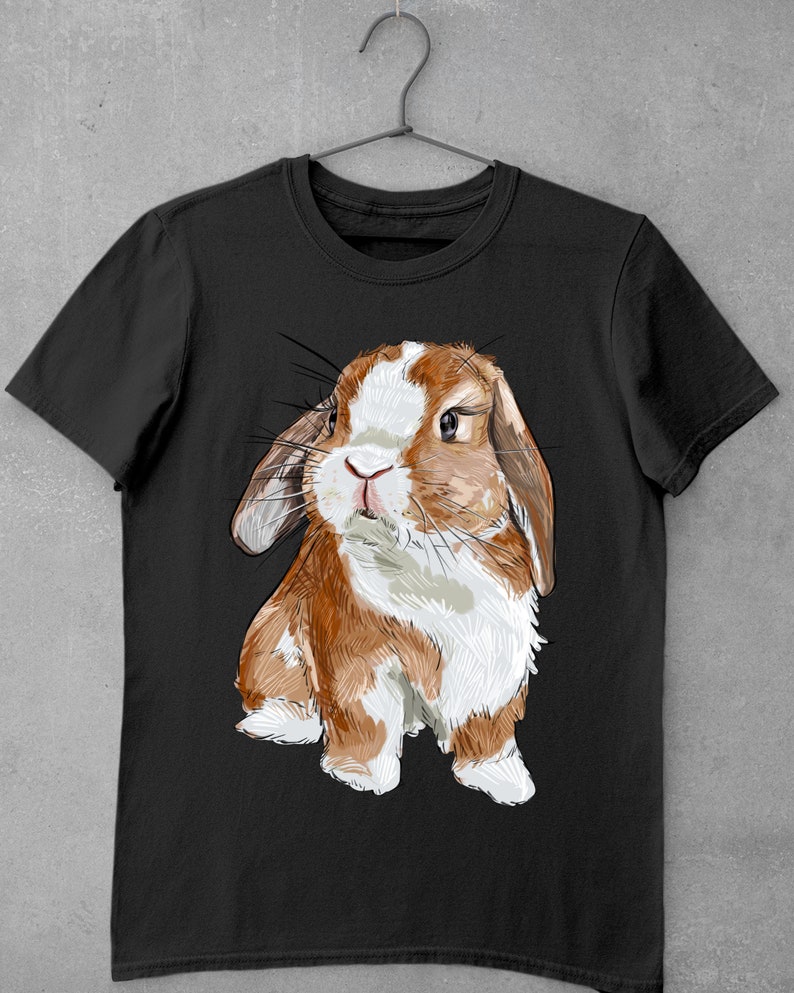 May include: A black t-shirt with a cartoon illustration of a brown and white lop-eared rabbit. The rabbit is looking directly at the viewer with a curious expression.