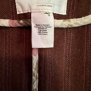 May include: A brown cotton jacket with a white floral print lining. The tag reads "UO" and "Made in Vietnam" with the RN and CA numbers. The size tag shows XS, S, M, and L.