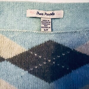Puede incluir: Un su&eacute;ter azul y blanco con un patr&oacute;n de diamantes. El su&eacute;ter tiene una etiqueta de Free People que dice "Made in Australia, Fabrique aux Australie, S/P".
