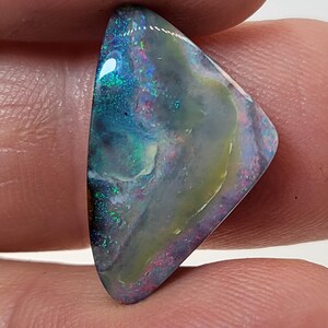 May include: A triangular, iridescent opal gemstone with a blue, green, and white color pattern. The opal is set in a silver ring.