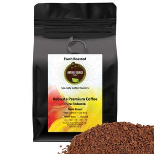 May include: A black bag of Nature Source Coffee's Robusta Premium Coffee, Dark Roast. The bag features a label with the text "Fresh Roasted" and "Specialty Coffee Roasters." The label also lists "High Caffeine" and "Low Acid" features. A pile of ground coffee is in the foreground.
