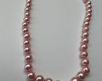 May include: A pink pearl necklace with a gold clasp.
