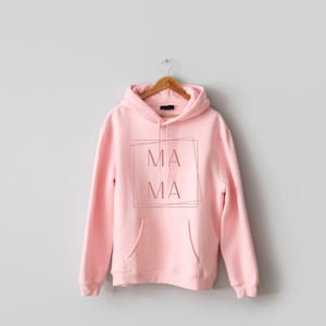 May include: A pink hoodie with a pocket and a graphic that says "MA MA" in a box.