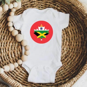 May include: White baby onesie with a red maple leaf design. The maple leaf is filled with the flags of India, Jamaica, and Canada.