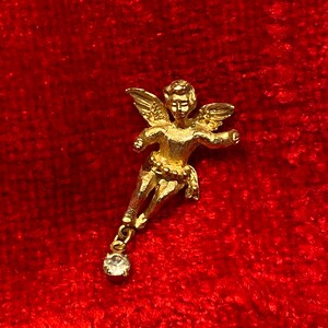 May include: Gold angel charm with a single clear rhinestone dangling from the bottom. The angel is depicted with wings outstretched and a single rhinestone on its chest.